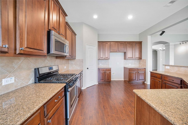 5125 Sugarberry Dr, Mckinney, TX 75071 - kitchen with appliances with stainless steel finishes, arched walkways, brown cabinets, decorative columns, and recessed lighting