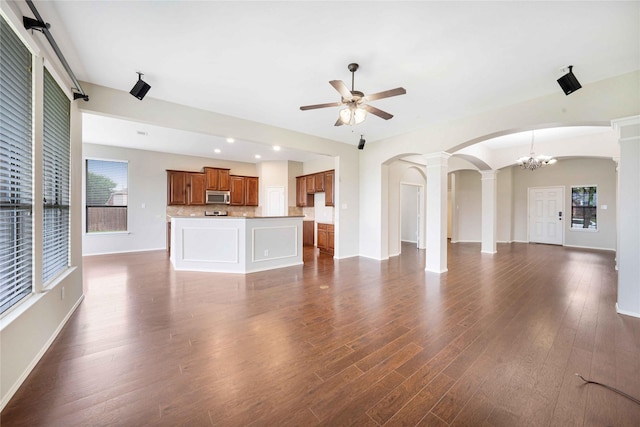 5125 Sugarberry Dr, Mckinney, TX 75071 - unfurnished living room with decorative columns, a ceiling fan, arched walkways, dark wood finished floors, and a chandelier