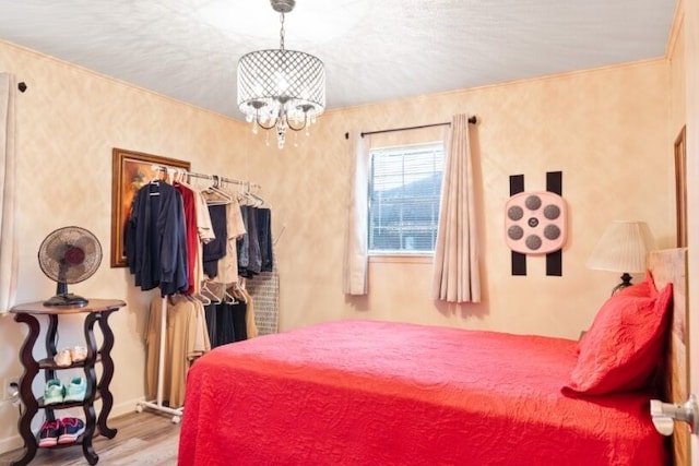324 Peachtree St, Fairfield, TX 75840 - bedroom featuring wood finished floors, a chandelier, a spacious closet, baseboards, and crown molding