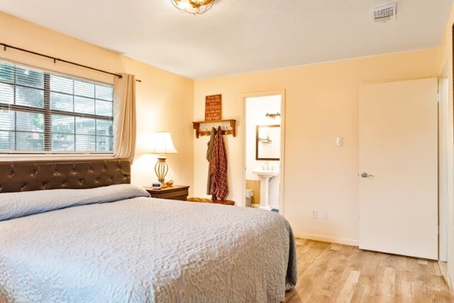 324 Peachtree St, Fairfield, TX 75840 - bedroom featuring light wood-type flooring, connected bathroom, and baseboards