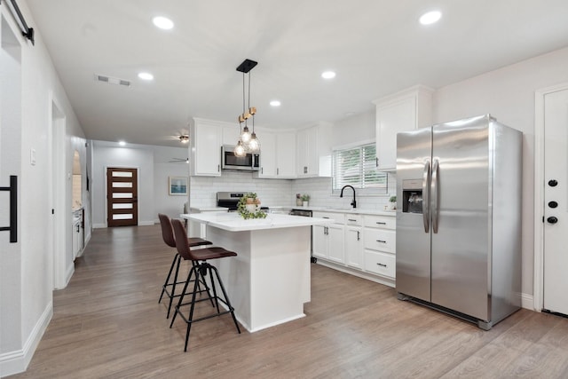 2123 Wheaton Dr, Richardson, TX 75081 - kitchen featuring appliances with stainless steel finishes, a center island, light wood-style flooring, decorative backsplash, and baseboards