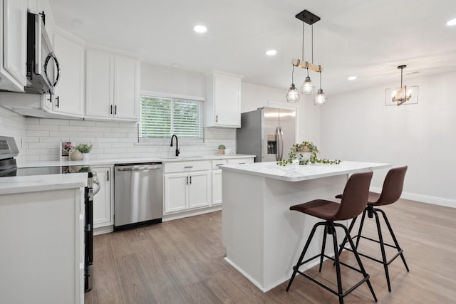 2123 Wheaton Dr, Richardson, TX 75081 - kitchen featuring stainless steel appliances, a sink, light wood-style floors, tasteful backsplash, and a breakfast bar area