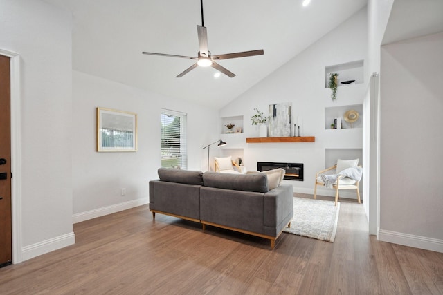 2123 Wheaton Dr, Richardson, TX 75081 - living area with ceiling fan, a glass covered fireplace, high vaulted ceiling, baseboards, and wood finished floors