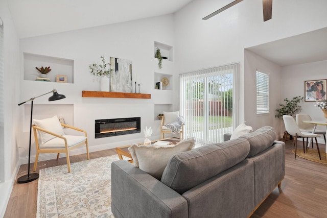 2123 Wheaton Dr, Richardson, TX 75081 - living room featuring a glass covered fireplace, a ceiling fan, wood finished floors, built in features, and baseboards