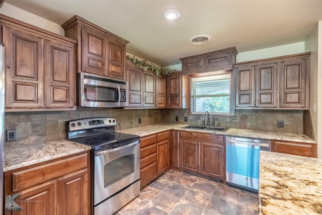 5626 Meadow Dr, Abilene, TX 79606 - kitchen featuring appliances with stainless steel finishes, a sink, backsplash, light stone counters, and brown cabinets