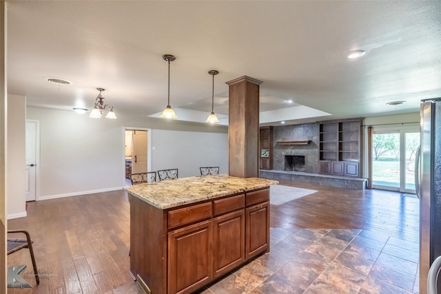 5626 Meadow Dr, Abilene, TX 79606 - kitchen with baseboards, brown cabinetry, a fireplace, open floor plan, and decorative light fixtures