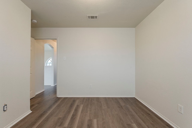 1720 Triumph Trl, Arlington, TX 76002 - empty room featuring arched walkways, dark wood-type flooring, baseboards, and a smoke detector
