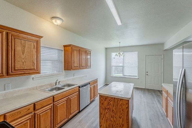 1720 Triumph Trl, Arlington, TX 76002 - kitchen with appliances with stainless steel finishes, a sink, brown cabinetry, light wood finished floors, and a kitchen island