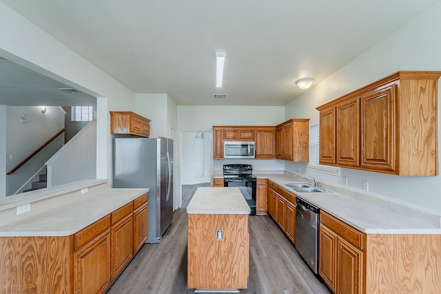 1720 Triumph Trl, Arlington, TX 76002 - kitchen featuring appliances with stainless steel finishes, a sink, light wood-style flooring, light countertops, and a center island