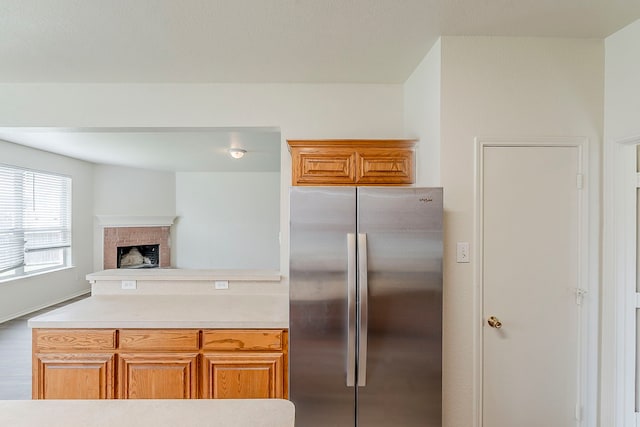 1720 Triumph Trl, Arlington, TX 76002 - kitchen with freestanding refrigerator, light countertops, a peninsula, a brick fireplace, and brown cabinets