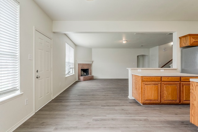 1720 Triumph Trl, Arlington, TX 76002 - kitchen with a fireplace, light countertops, arched walkways, brown cabinets, and light wood-type flooring