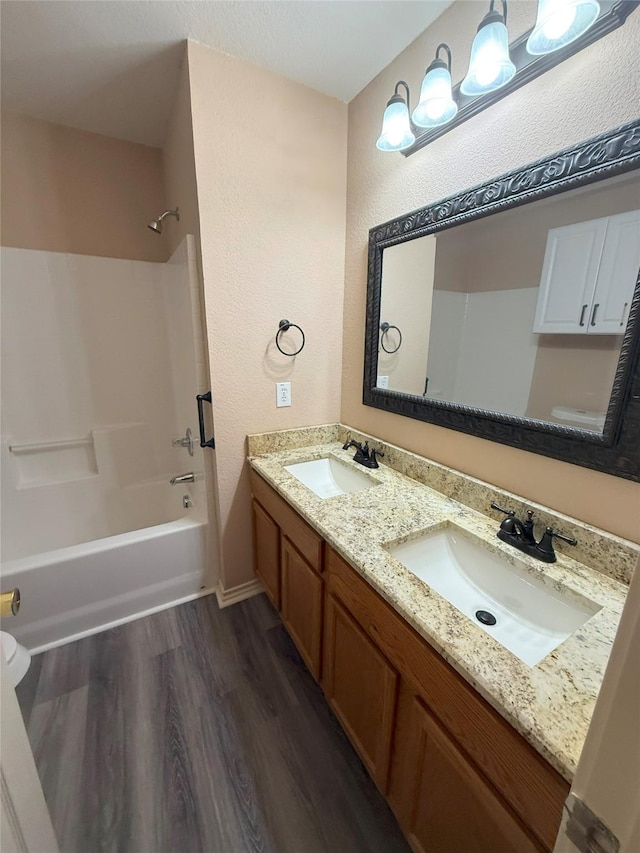 716 Riverhead Dr, Wylie, TX 75098 - full bathroom with wood finished floors, double vanity, washtub / shower combination, and a textured wall