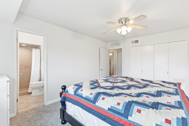 bedroom featuring light carpet, connected bathroom, light tile patterned floors, a closet, and ceiling fan