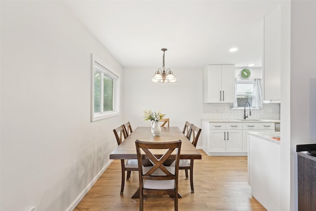 dining space featuring light wood-style floors, a chandelier, and baseboards