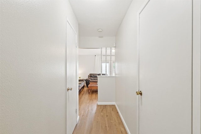 hallway featuring light wood-type flooring and baseboards