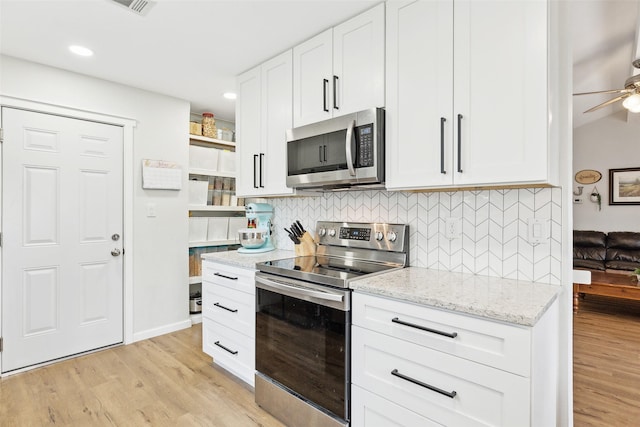 kitchen featuring appliances with stainless steel finishes, open shelves, tasteful backsplash, white cabinetry, and light stone counters