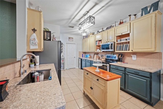 1412 Millbrook Ln, Wylie, TX 75098 - kitchen with appliances with stainless steel finishes, cream cabinets, light countertops, and tasteful backsplash