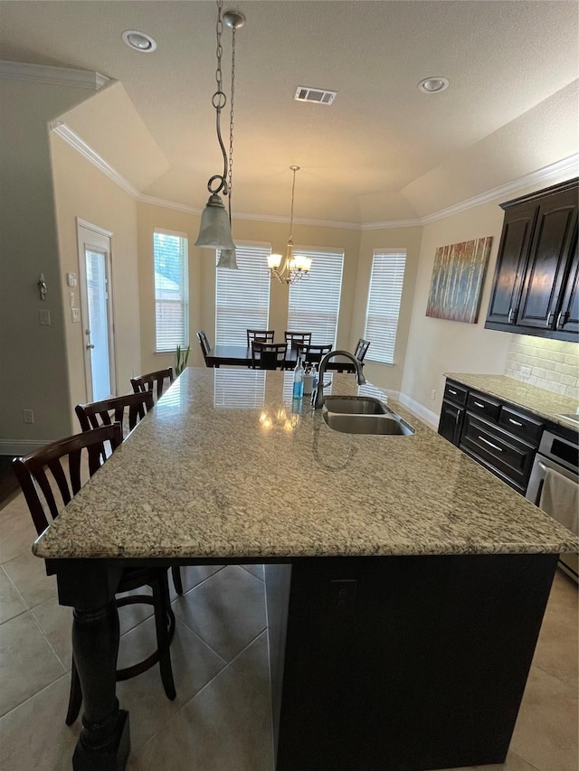 340 Prince John Dr, Saginaw, TX 76179 - kitchen with a sink, crown molding, a kitchen island with sink, light stone counters, and a breakfast bar area