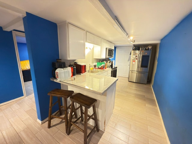 kitchen featuring stainless steel appliances, white cabinets, baseboards, and light countertops