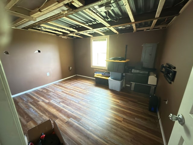 miscellaneous room featuring wood finished floors, electric panel, and baseboards