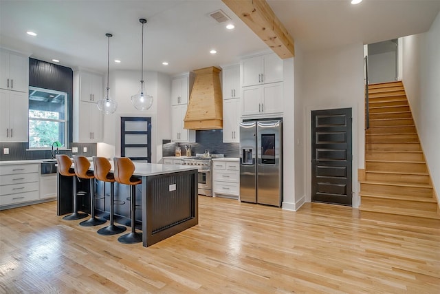 1014 Eagles Ridge Ct, Weatherford, TX 76087 - kitchen featuring appliances with stainless steel finishes, custom range hood, light wood finished floors, a center island, and a breakfast bar area