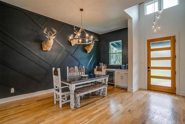 1014 Eagles Ridge Ct, Weatherford, TX 76087 - dining room with wine cooler, a chandelier, light wood-style floors, baseboards, and a decorative wall