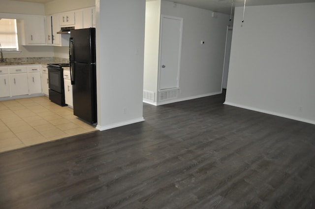 412 Poplar St, Italy, TX 76651 - kitchen with black appliances, wood finished floors, white cabinetry, under cabinet range hood, and baseboards