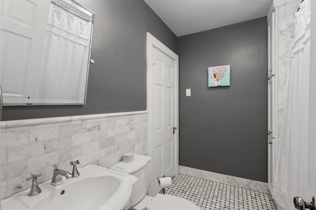 4233 Pershing Ave, Fort Worth, TX 76107 - bathroom featuring a sink, toilet, tile walls, baseboards, and wainscoting