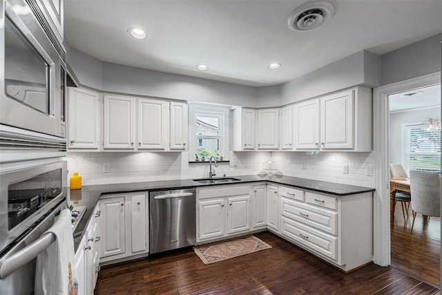 4233 Pershing Ave, Fort Worth, TX 76107 - kitchen with stainless steel appliances, a sink, dark countertops, white cabinetry, and backsplash
