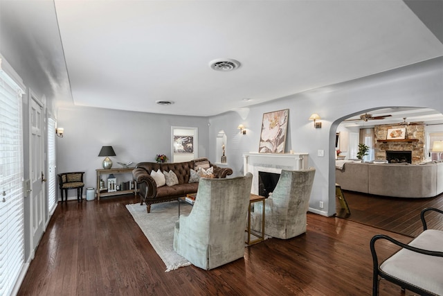 4233 Pershing Ave, Fort Worth, TX 76107 - living area featuring a stone fireplace, arched walkways, healthy amount of natural light, and dark wood-style floors