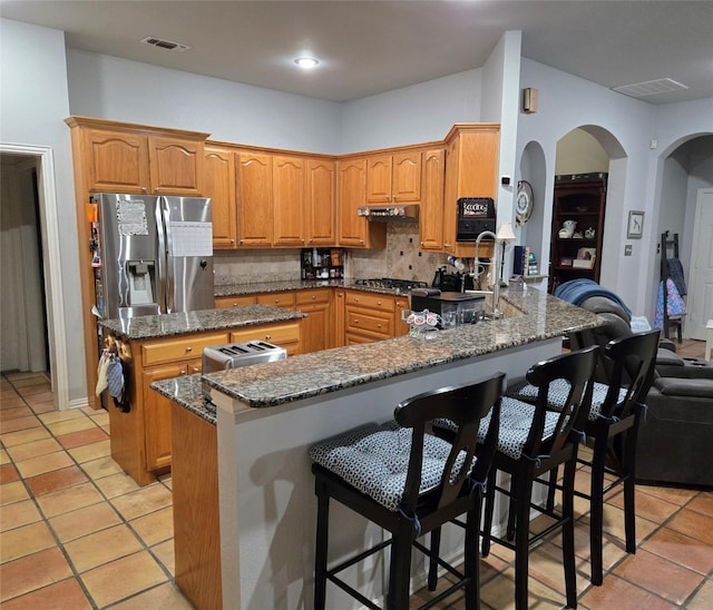 104 Olives Br, Shady Shores, TX 76208 - kitchen featuring a peninsula, dark stone counters, backsplash, a kitchen island, and appliances with stainless steel finishes
