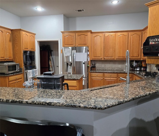 104 Olives Br, Shady Shores, TX 76208 - kitchen with appliances with stainless steel finishes, dark stone counters, tasteful backsplash, brown cabinets, and recessed lighting