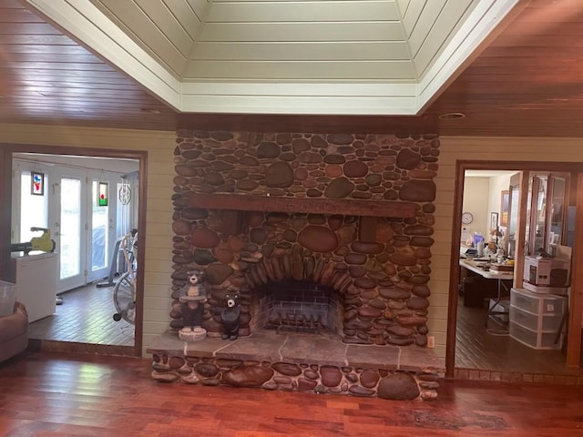 909 Mckinney Ave, Princeton, TX 75407 - living room with a stone fireplace, wood finished floors, french doors, wooden walls, and wooden ceiling