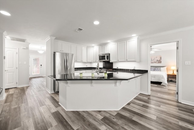 200 Oakview Cir, Mexia, TX 76667 - kitchen featuring stainless steel appliances, crown molding, a peninsula, wood finished floors, and dark countertops