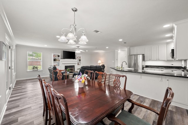200 Oakview Cir, Mexia, TX 76667 - dining room with a chandelier, light wood-style flooring, crown molding, recessed lighting, and a fireplace