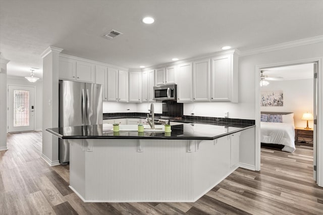 200 Oakview Cir, Mexia, TX 76667 - kitchen with appliances with stainless steel finishes, dark countertops, wood finished floors, white cabinets, and ornamental molding