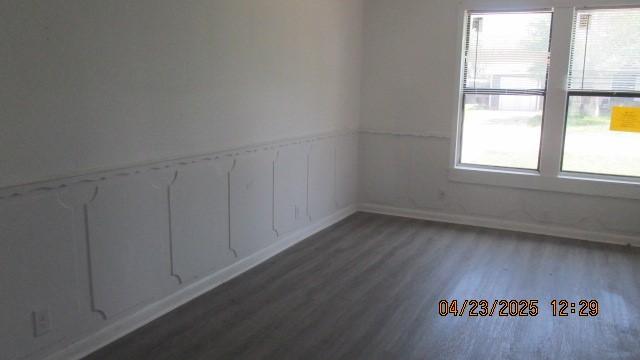 spare room with wood finished floors, a wainscoted wall, and baseboards