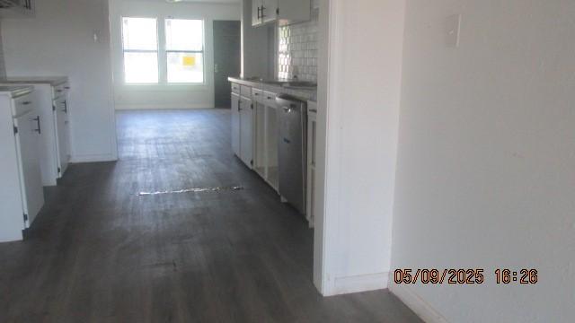 kitchen featuring dishwasher, dark wood finished floors, baseboards, and white cabinets