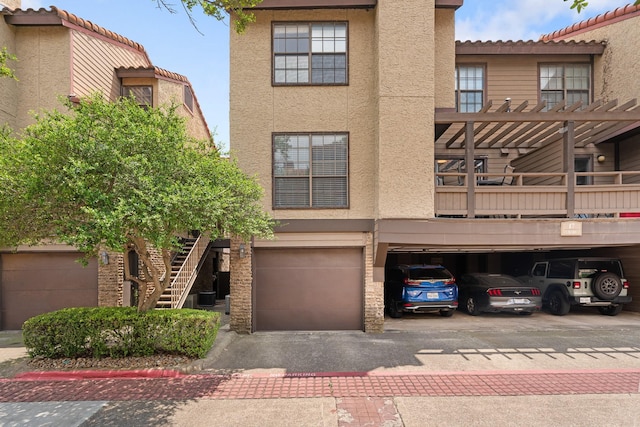 4800 Northway Dr Unit 17A, Dallas, TX 75206 - view of front of property with stucco siding, stairs, central AC unit, driveway, and an attached garage