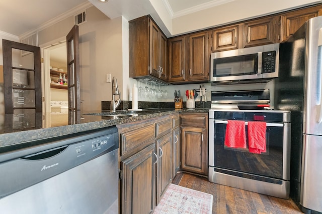 4800 Northway Dr Unit 17A, Dallas, TX 75206 - kitchen featuring appliances with stainless steel finishes, crown molding, dark wood finished floors, a sink, and dark stone countertops