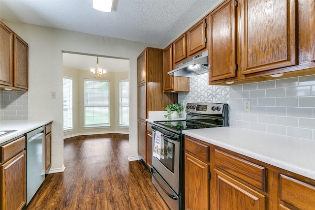 905 Wildwood Cir, Grapevine, TX 76051 - kitchen with stainless steel appliances, under cabinet range hood, brown cabinetry, dark wood-style flooring, and light countertops