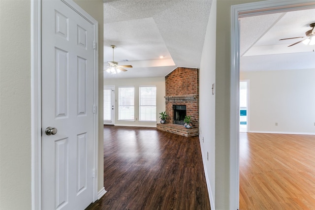 905 Wildwood Cir, Grapevine, TX 76051 - unfurnished living room featuring a ceiling fan, wood finished floors, a tray ceiling, and a textured ceiling