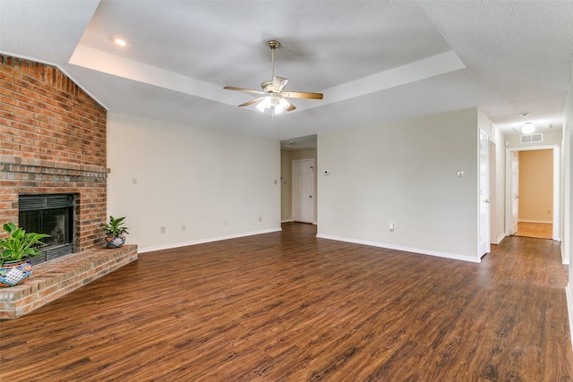 905 Wildwood Cir, Grapevine, TX 76051 - unfurnished living room with a raised ceiling, a ceiling fan, dark wood-style floors, baseboards, and a fireplace