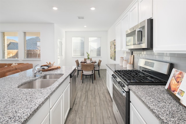 5836 Priory Dr, Celina, TX 76227 - kitchen with stainless steel appliances, a sink, light wood-style floors, recessed lighting, and white cabinets
