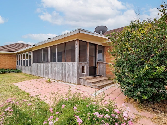 905 High Rd, Coleman, TX 76834 - back of property featuring a sunroom, a patio area, a lawn, and brick siding