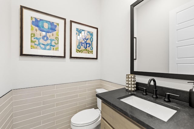 1015 Olympic Dr, Rockwall, TX 75087 - half bath featuring toilet, vanity, tile walls, and wainscoting