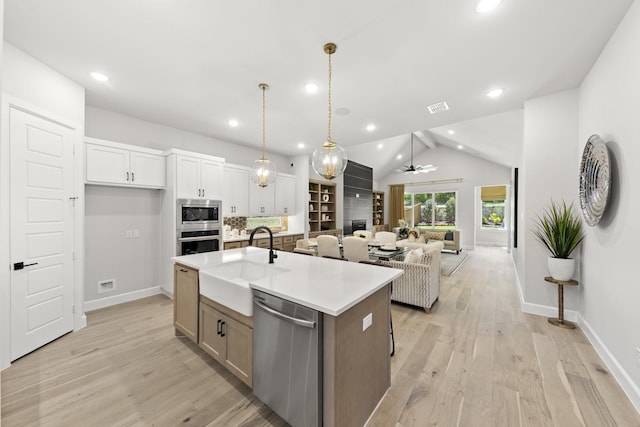 1015 Olympic Dr, Rockwall, TX 75087 - kitchen featuring stainless steel appliances, a sink, open floor plan, lofted ceiling, and a center island with sink