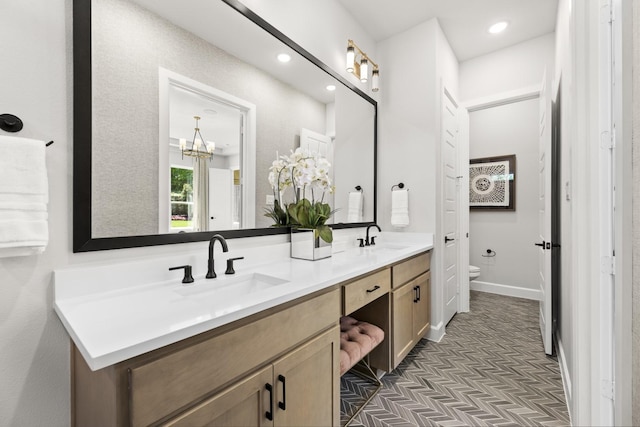 1015 Olympic Dr, Rockwall, TX 75087 - bathroom with toilet, double vanity, recessed lighting, baseboards, and a chandelier