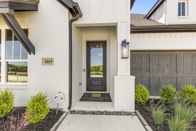 1015 Olympic Dr, Rockwall, TX 75087 - doorway to property featuring a shingled roof, board and batten siding, and brick siding
