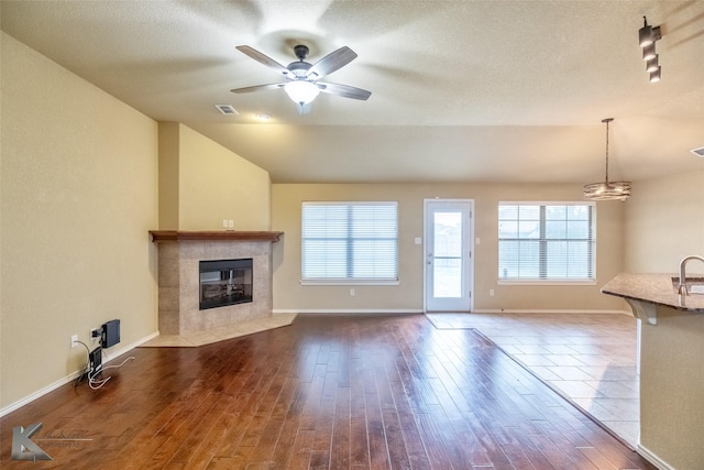 210 Miss Ellie Ln, Abilene, TX 79602 - unfurnished living room with a fireplace, dark wood-style flooring, vaulted ceiling, ceiling fan, and baseboards